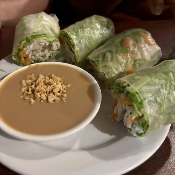 Four fresh spring rolls with chicken, vegetables, and rice noodles, served with peanut sauce.