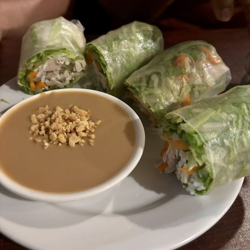 Four fresh spring rolls with chicken, vegetables, and rice noodles, served with peanut sauce.