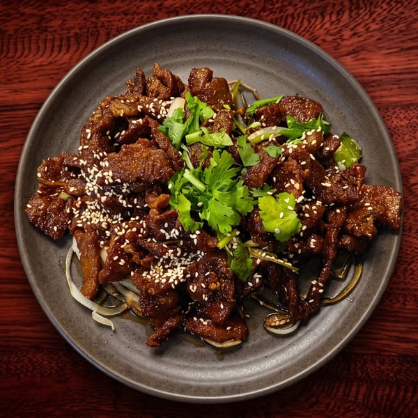 A dark plate of sesame beef with cilantro and onions on a dark wooden table.